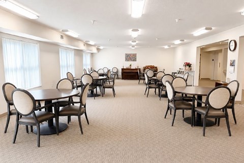 A room with tables and chairs and a clock on the wall.