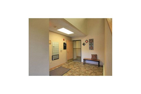 A hallway with a bench and a door at the end.