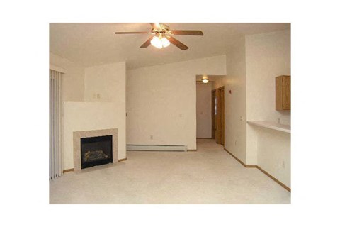 A living room with a fireplace and a ceiling fan.
