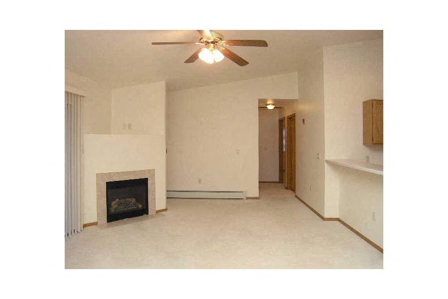A living room with a fireplace and a ceiling fan.