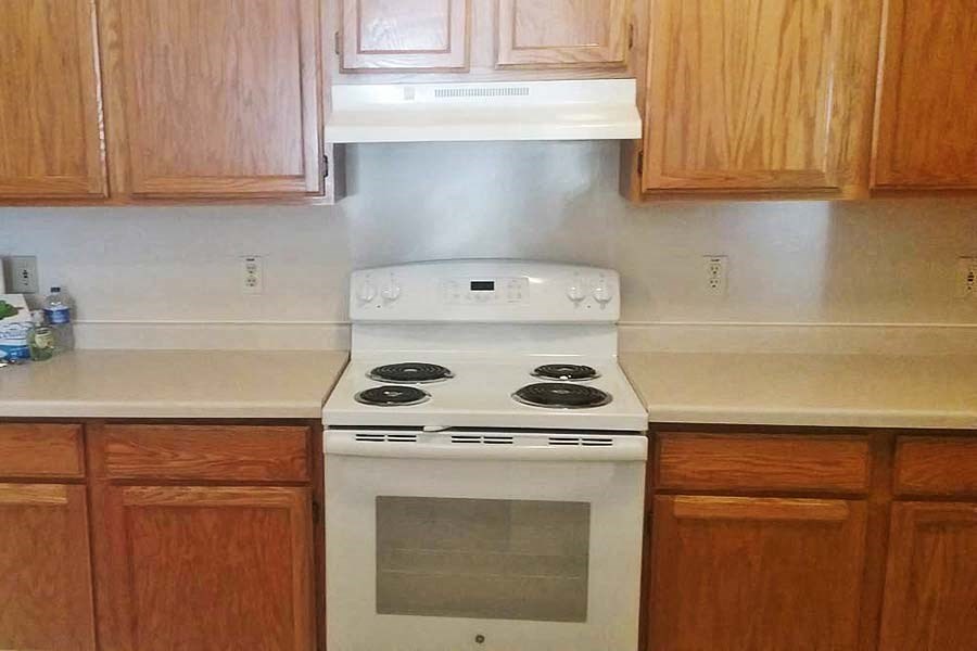 A white stove top oven with a glass door is in a kitchen with wooden cabinets.