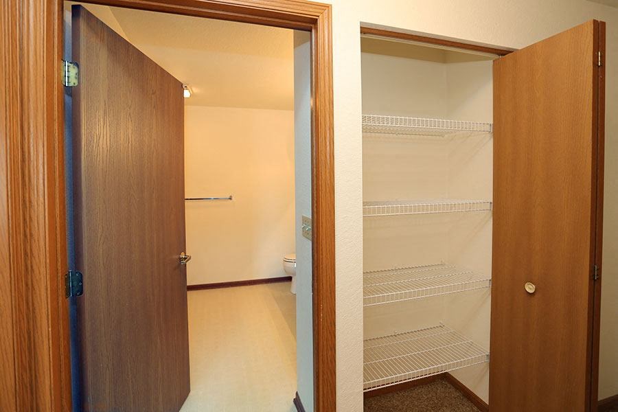 a bathroom with an empty closet and a open door