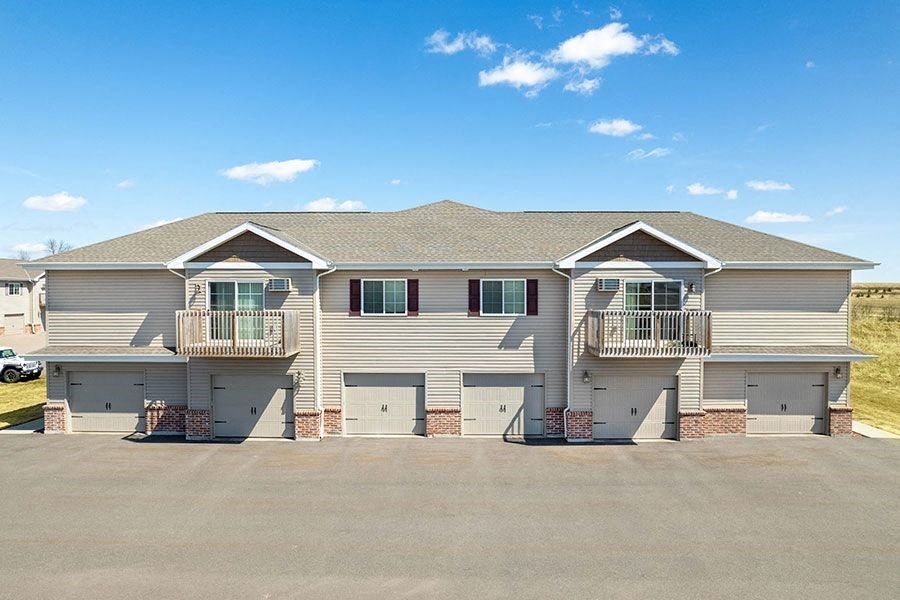 a gray house with two balconies and a parking lot