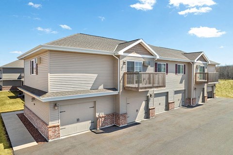 a beige house with a balcony and a driveway