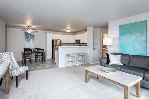 A living room with a grey couch, a coffee table, and a painting on the wall.