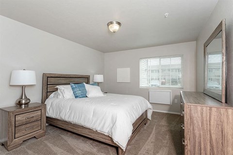 A bedroom with a bed, nightstand, and lamp.