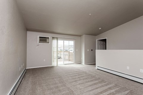 A spacious room with a carpeted floor and a window letting in natural light.