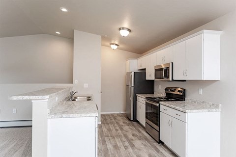 A kitchen with white cabinets and a black refrigerator.