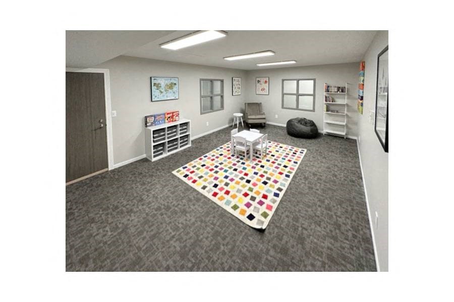 an empty classroom with a rug and a table and chairs