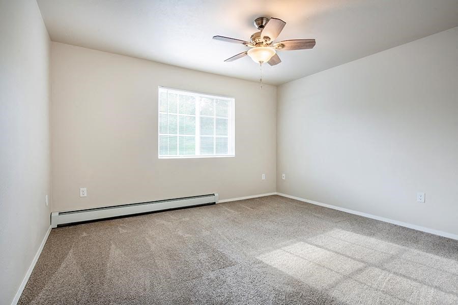 an empty room with a ceiling fan and a window