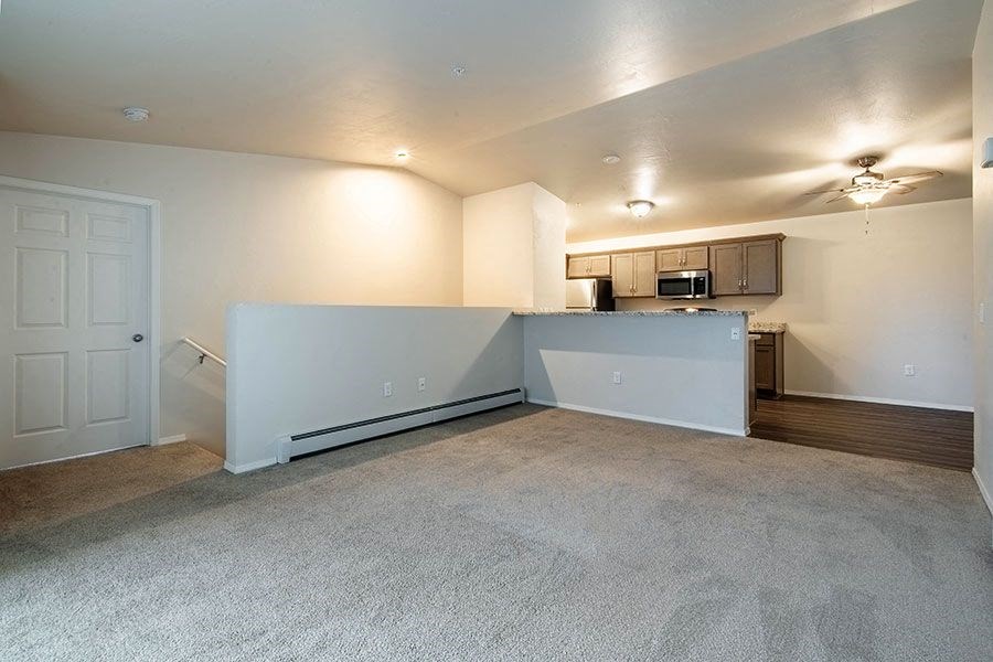 an empty living room with a kitchen and a door