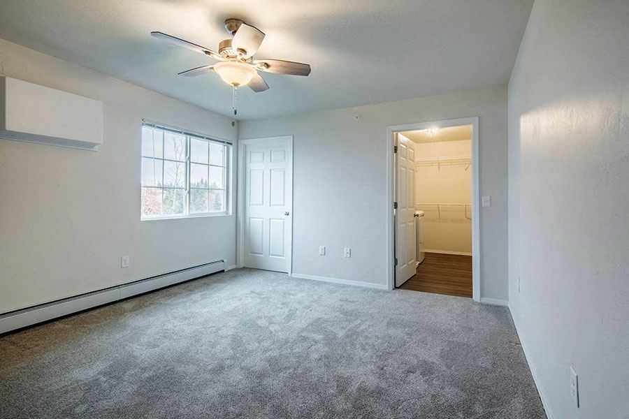 an empty living room with a ceiling fan      and a door