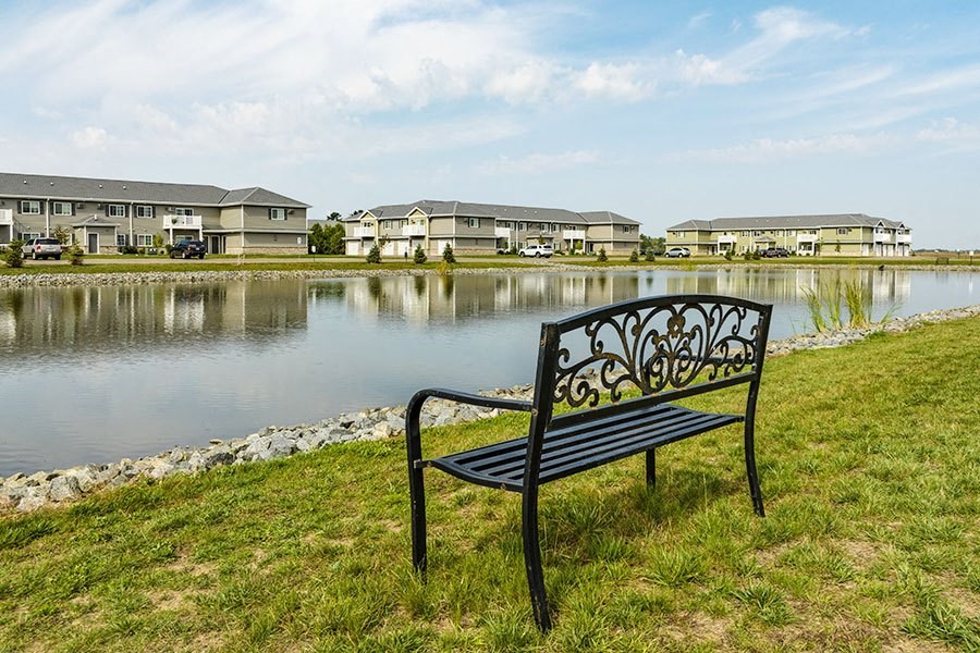 a bench sitting on the grass next to a lake