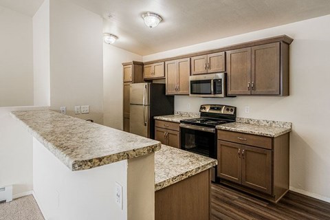 A kitchen with brown cabinets and granite countertops.