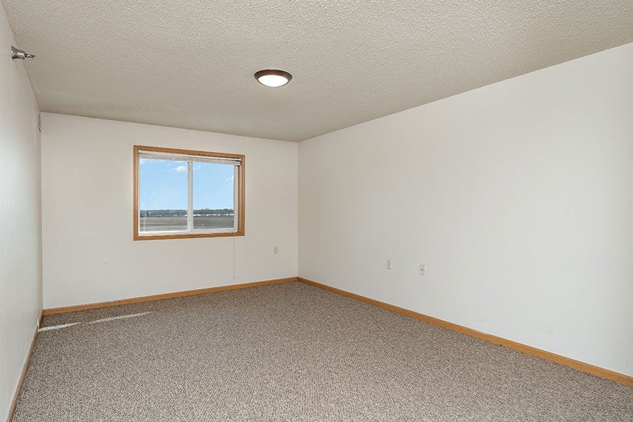 an empty room with a window and a carpet