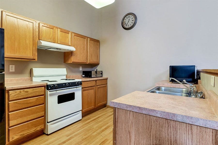 a kitchen with a stove a sink and a clock