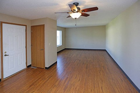 an empty living room with wood floors and a ceiling fan