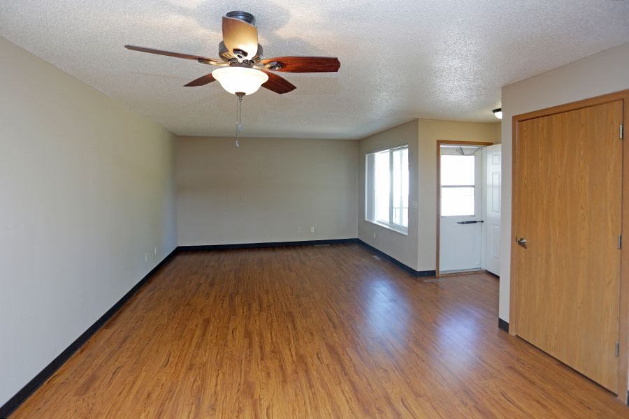 a empty living room with wood floors and a ceiling fan