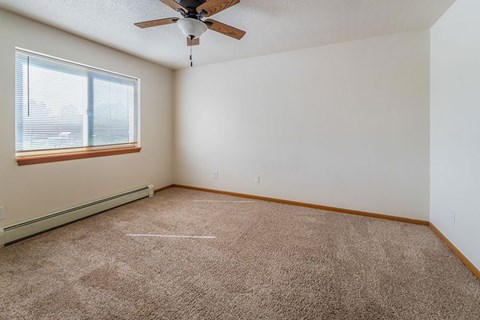 A room with a ceiling fan and carpeted floor.