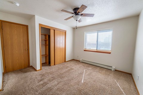 A room with a ceiling fan and a window with blinds.