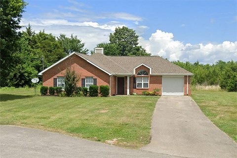 a brick house with a driveway in front of a field