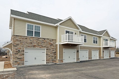 a beige house with a balcony and garage doors