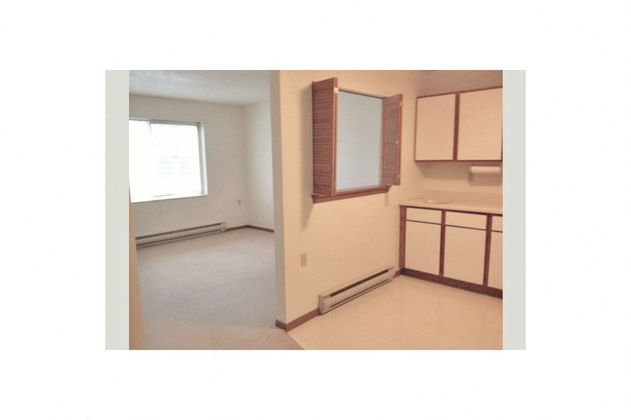 an empty room with a kitchen and a window