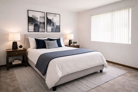 A bedroom with a large bed and two lamps on side tables.