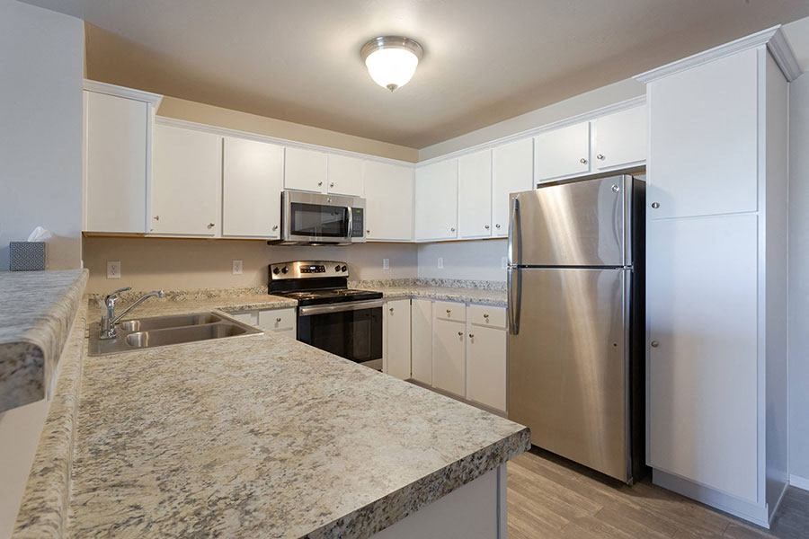a kitchen with white cabinets and a stainless steel refrigerator
