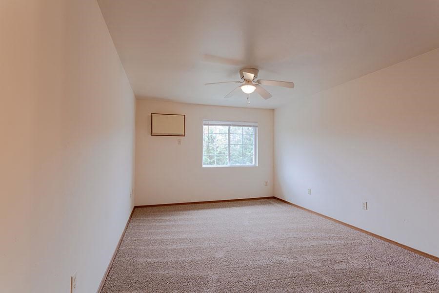 an empty room with a ceiling fan and a window