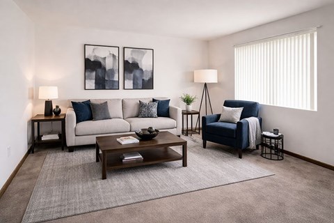 A living room with a grey couch, a blue chair, a wooden coffee table, and two lamps.