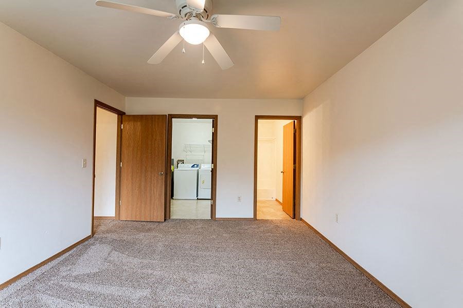 a empty living room with a ceiling fan      and a kitchen