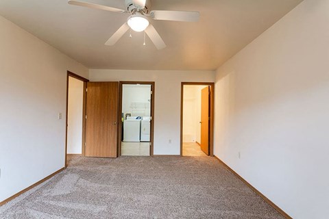 a empty living room with a ceiling fan      and a kitchen