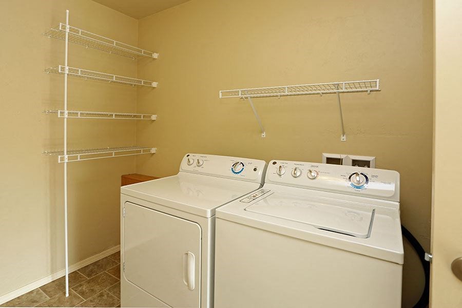 two washers and dryers in a laundry room with shelves