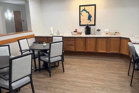 A kitchen with a table and chairs and a framed picture of a state on the wall.