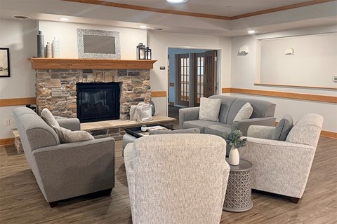 A living room with a stone fireplace and grey couches.