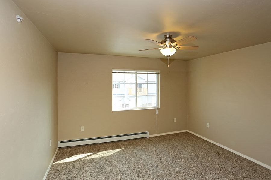 an empty room with a ceiling fan and a window
