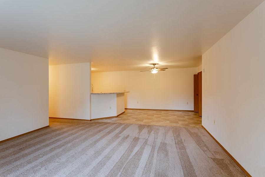 an empty living room and kitchen with a ceiling fan