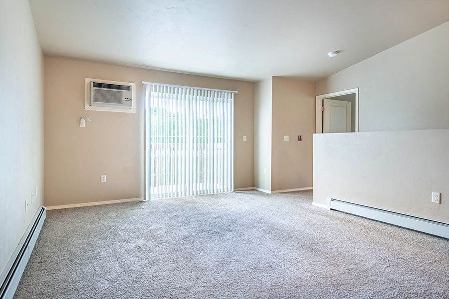 an empty living room with a heater and a window