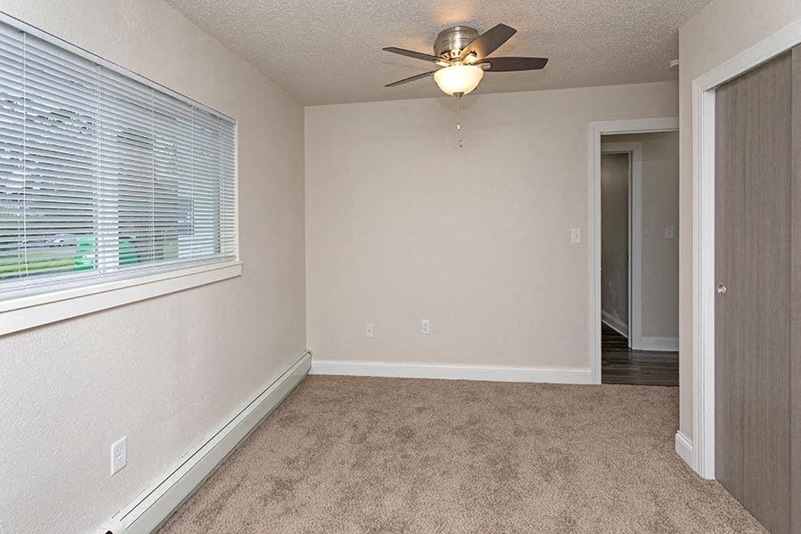 an empty bedroom with a ceiling fan and a window