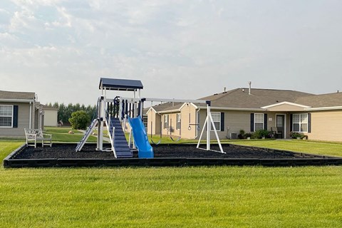 a playground with a swing set in front of houses