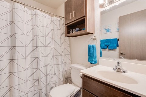 A bathroom with a white sink, toilet, and a shower curtain with a geometric pattern.