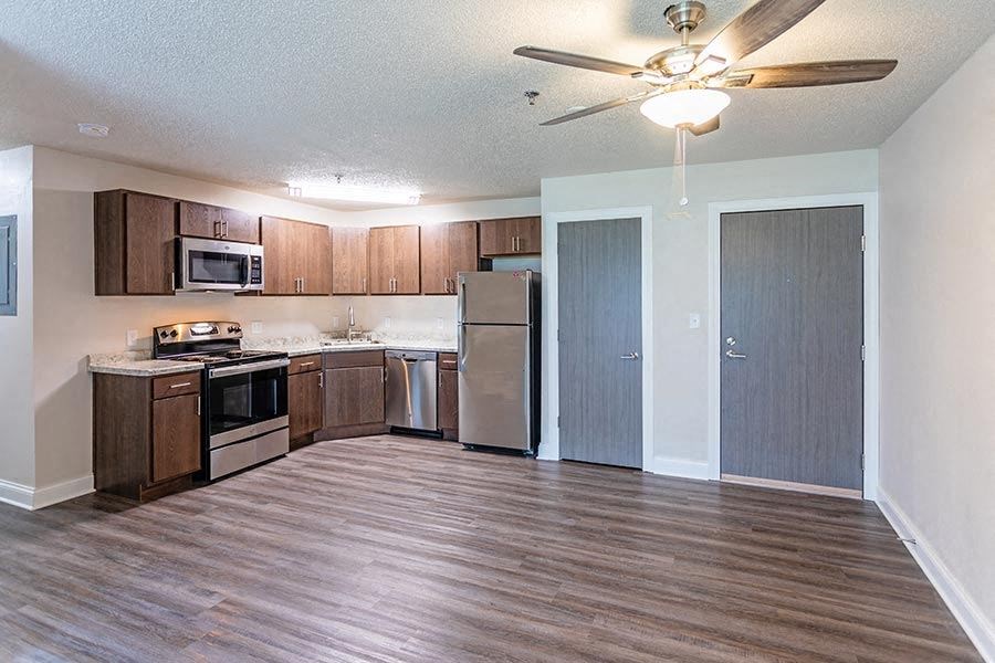 an empty kitchen with a ceiling fan and a refrigerator