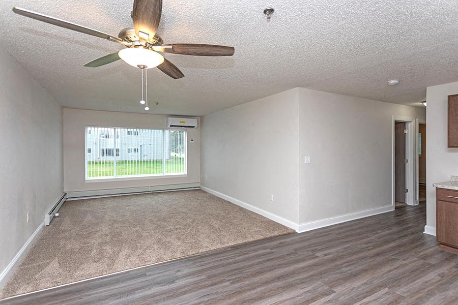 an empty living room with a ceiling fan