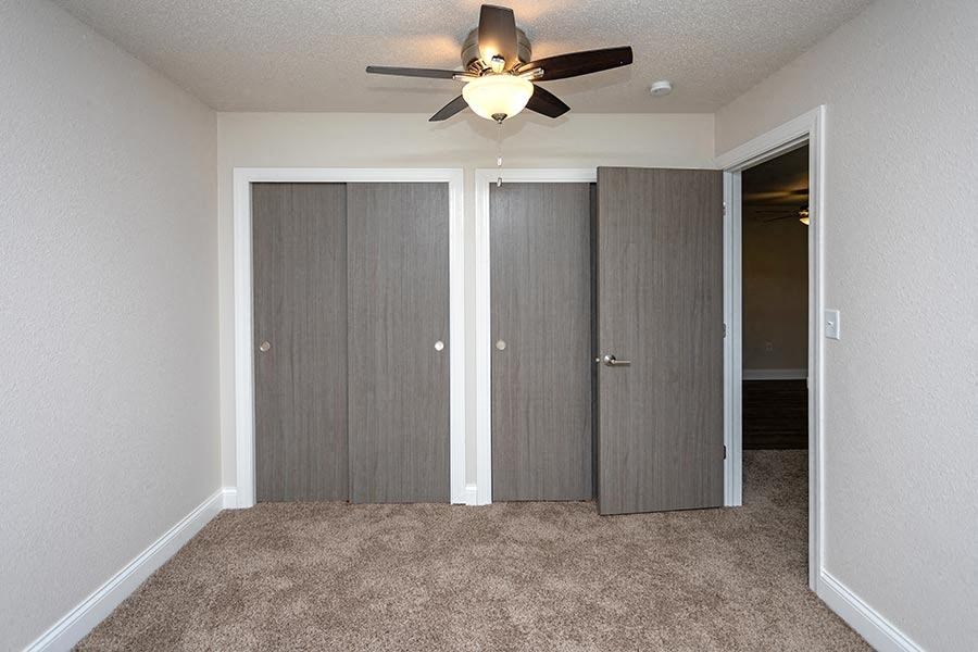 an empty bedroom with a ceiling fan and closet