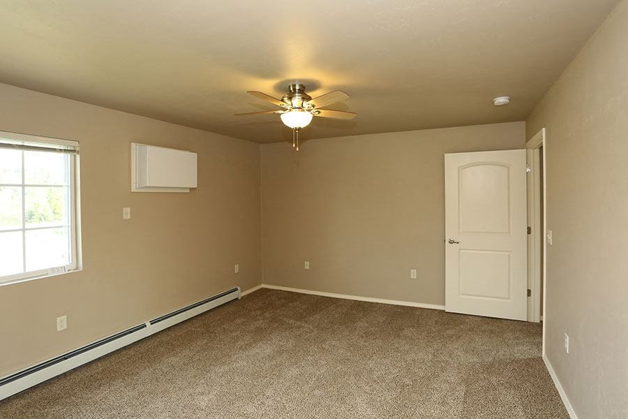 an empty room with a ceiling fan and a white door