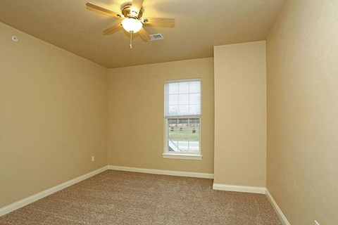 an empty room with a ceiling fan and a window