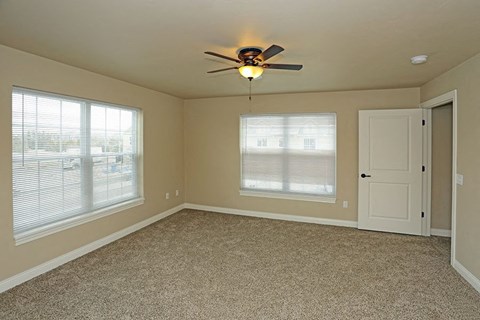 an empty bedroom with a ceiling fan and a door
