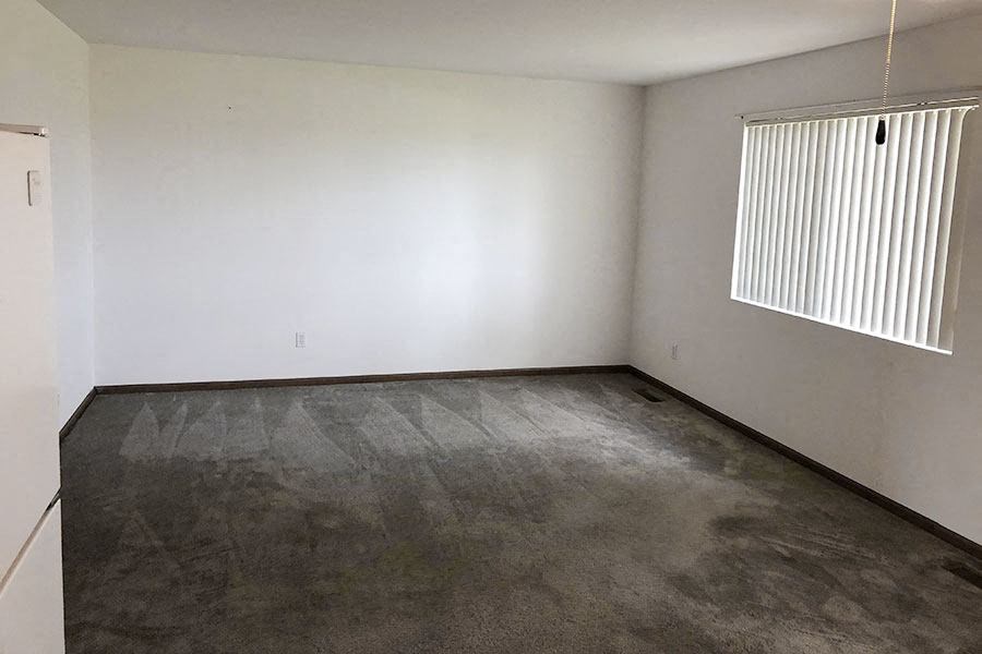 an empty room with a window and a concrete floor