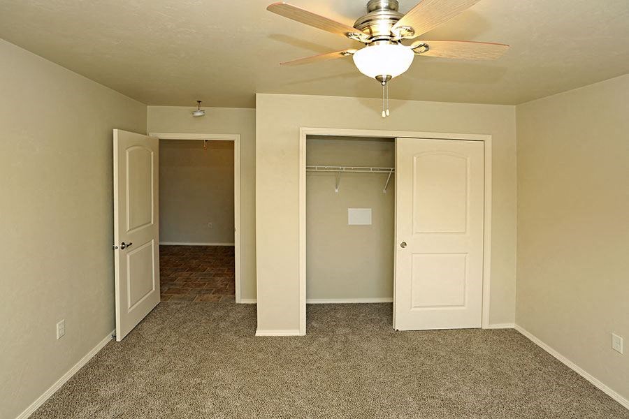 an empty bedroom with a ceiling fan and a closet